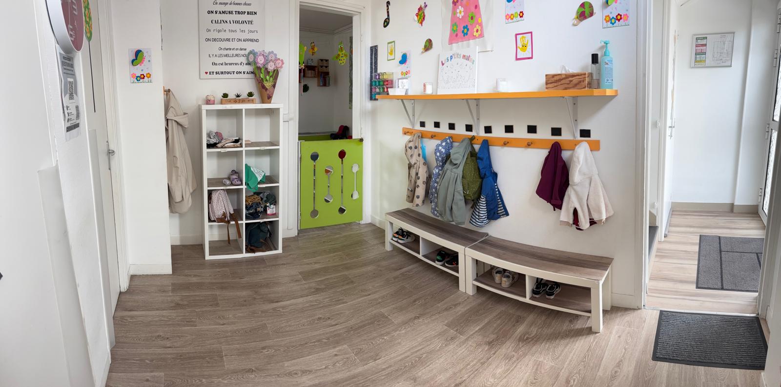 Sas d'accueil de la MAM Les P'ti Malins avec porte-manteaux, casiers et bancs pour les enfants